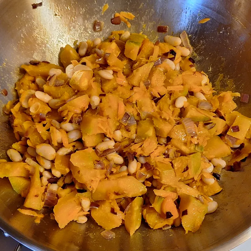 Zucca e fagioli uniti al soffritto di cipolla e carota in padella.