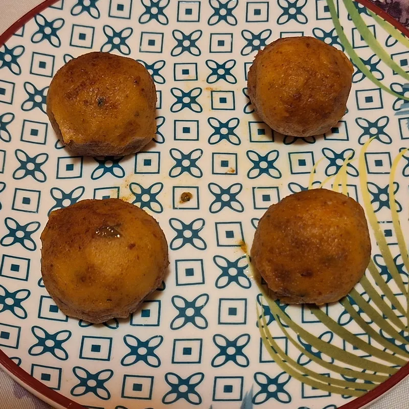 Quattro polpettine di zucca dorate, ripassate in padella, servite su un piatto decorato.