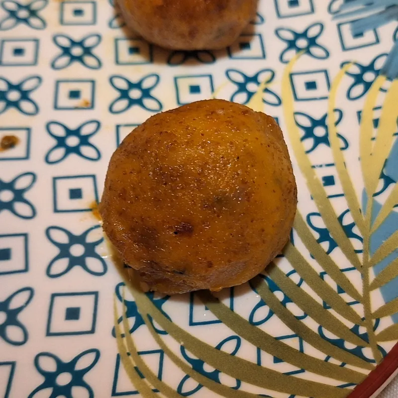 Primo piano di una polpettina di zucca dorata con crosta leggermente caramellata.