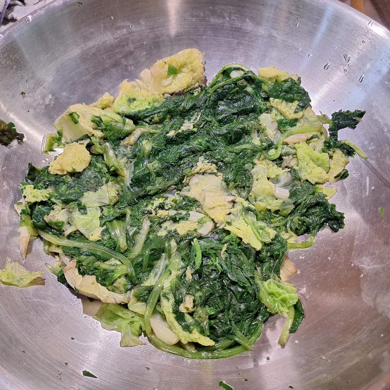 In questo caso ho bollito e poi scottato un misto di verdure a foglia, tutto nella stessa padella. Come si vede le verdure sono ancora molto umide, quindi vanno scolate e strizzate prima di usarle per formare il ripieno