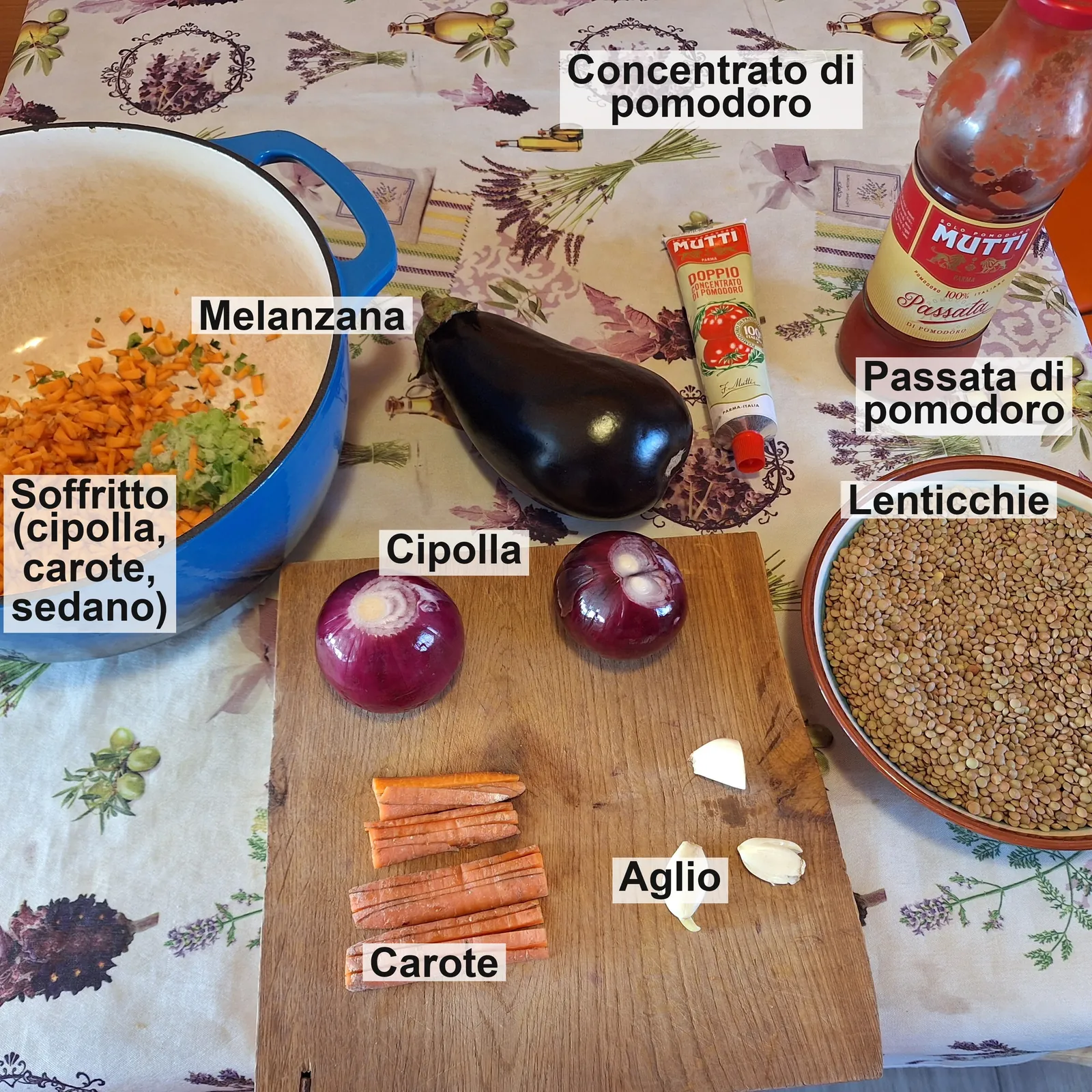 Gli ingredienti etichettati: il soffritto di cipolla, carote e sedano nella pentola, melanzana, concentrato di pomodoro, passata, cipolla, carote, aglio e lenticchie.